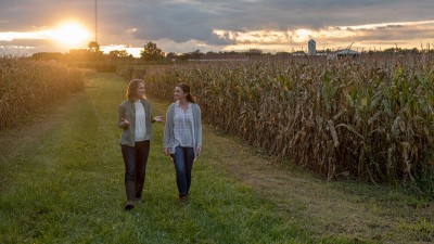 Two people in discussion walking through a field, representing what students will learn with Ohio State's online agriculture masters degree